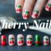 Close-up of a hand flaunting a red manicure adorned with cherry designs. Below, a display showcases various artificial nails with similar cherry patterns in green and red, reminiscent of Pinterest inspirations. A nail polish bottle and brush sit in the background. Text reads Cherry Nails.