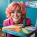 A creative entrepreneur with bright pink hair and glasses brings old furniture to life, transforming pieces into colorful works of art in her lively studio—a testament to her passion for artistic furniture flipping as a thriving side hustle.